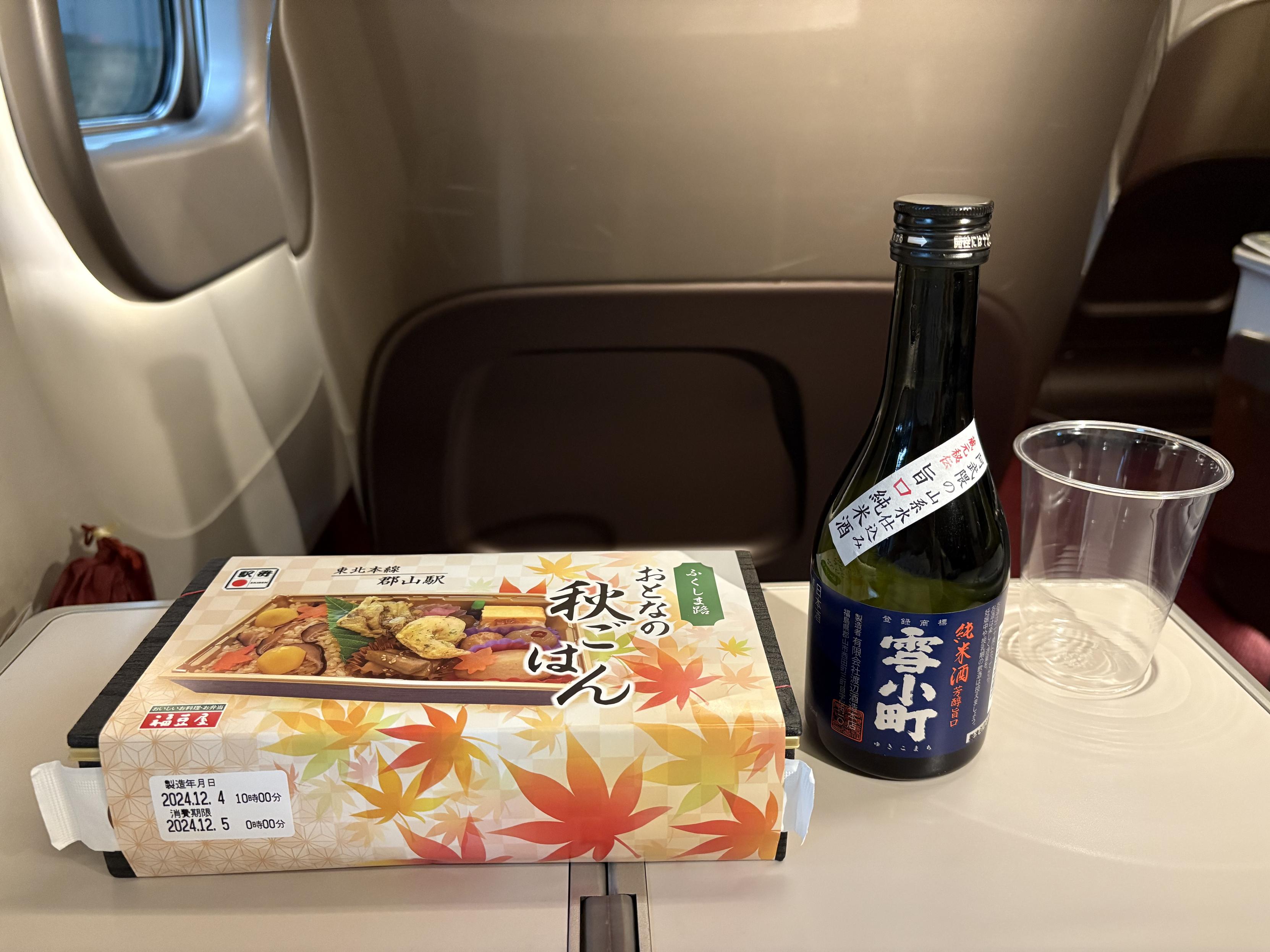 東北新幹線E5系グランクラス車内のテーブルに置いた駅弁と日本酒。
駅弁は福豆屋『ふくしま路おとなの秋ごはん』
日本酒は『雪小町』